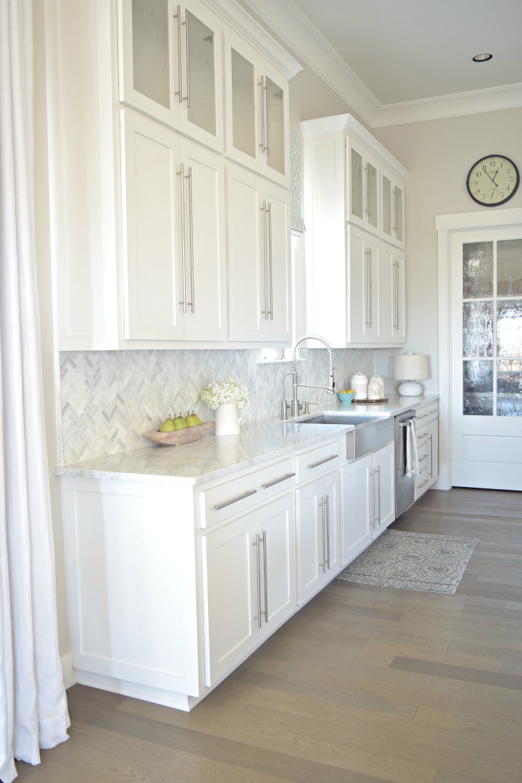 white kitchen stainless farmhouse sink herringbone backsplash carriara marble counter tops