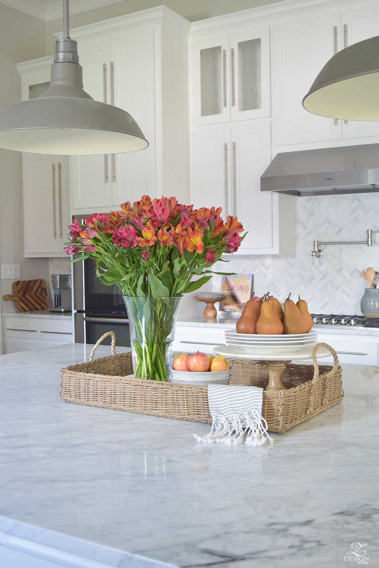 kitchen-island-styling-tips-with-baskets-fruit-and-flowers-carrara-marble-white-kitchen-herrinbone-backsplash-tile-1