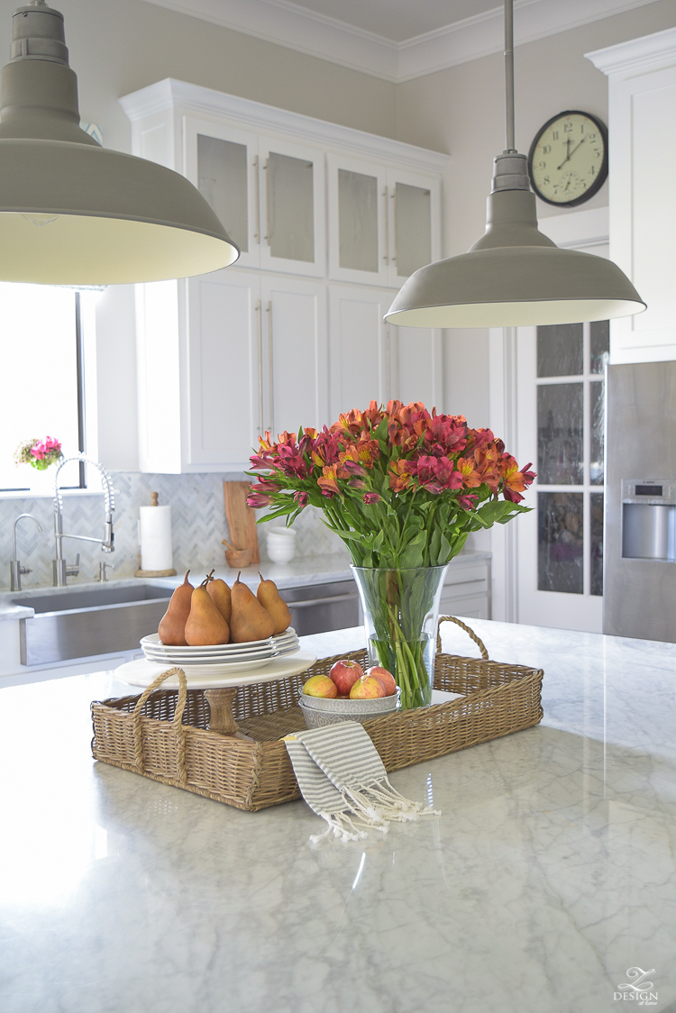 kitchen-island-styling-tips-with-baskets-fruit-and-flowers-carrara-marble-white-kitchen-herrinbone-backsplash-tile