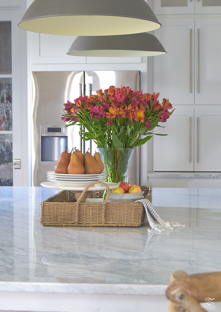 kitchen-island-styling-tips-with-baskets-fruit-and-flowers-carrara-marble-white-kitchen-herrinbone-backsplash-tile-4