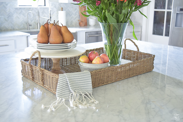 kitchen-island-styling-tips-with-baskets-fruit-and-flowers-carrara-marble-white-kitchen-herrinbone-backsplash-tile-5