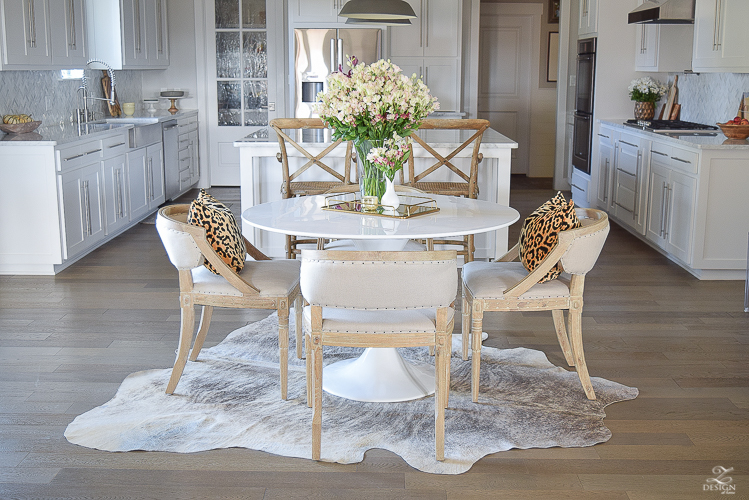 get-the-curl-out-of-cowhide-rug-white-farmhouse-kitchen-white-tulip-table-white-carrara-marble-marble-herringbone-tile-backsplash-2