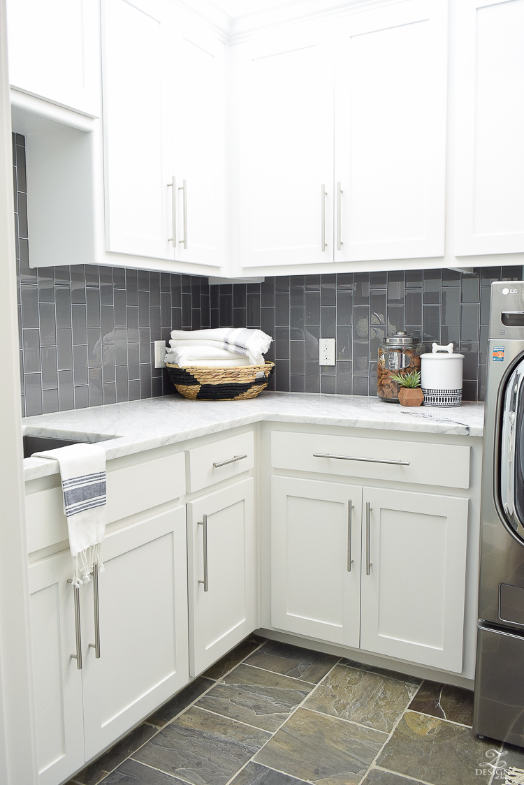 Beautiful Laundry Room Ideas White shaker cabinets large stainless bar pulls carrara marble counter tops gray glass subway tile laid vertiacally marble in the laundry room slate tile floors-2