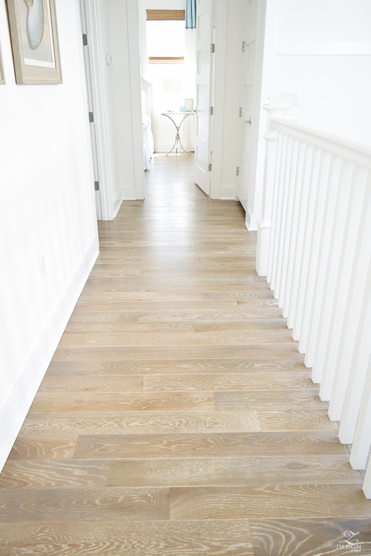 grid wall pattern in staircase with white walls blonde distressed hardwood floors chrome coastal chandelier beach house design coastal house decor how to design a beach house-2