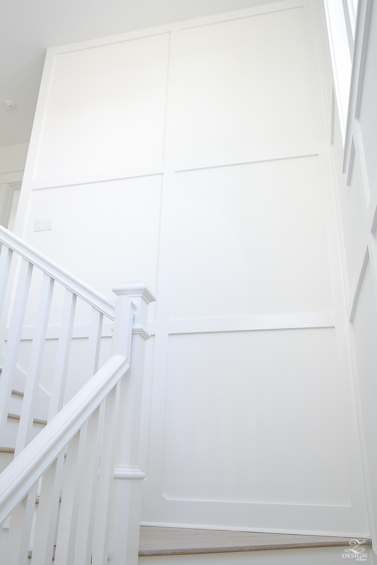 grid wall pattern in staircase with white walls blonde distressed hardwood floors chrome coastal chandelier beach house design coastal house decor how to design a beach house-4