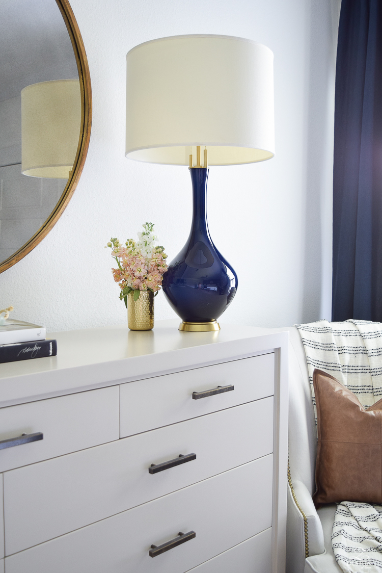 transitional style bedroom decor navy lamp with brass base round gold mirror modern gray dresser gold pencil cup-1