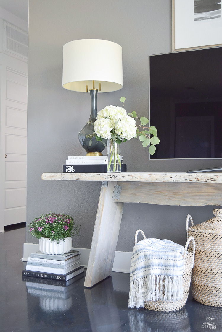 Fall Home Tour Decorating with books gray and brass table lamp distressed modern console table black concrete floors books stacked on floor with plant on top white fluted pot-1