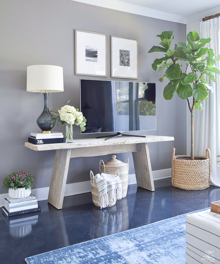 Fall Home Tour modern distressed console table tv gallery wall fig tree in large basket books stacked on floor gray and brass table lamp throws in lidded baskets gray accent wall-2