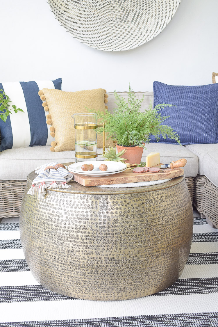 Sustainably sourced outdoor pillows, coffee table in hammered gold, cheese board and utensils made from olive wood