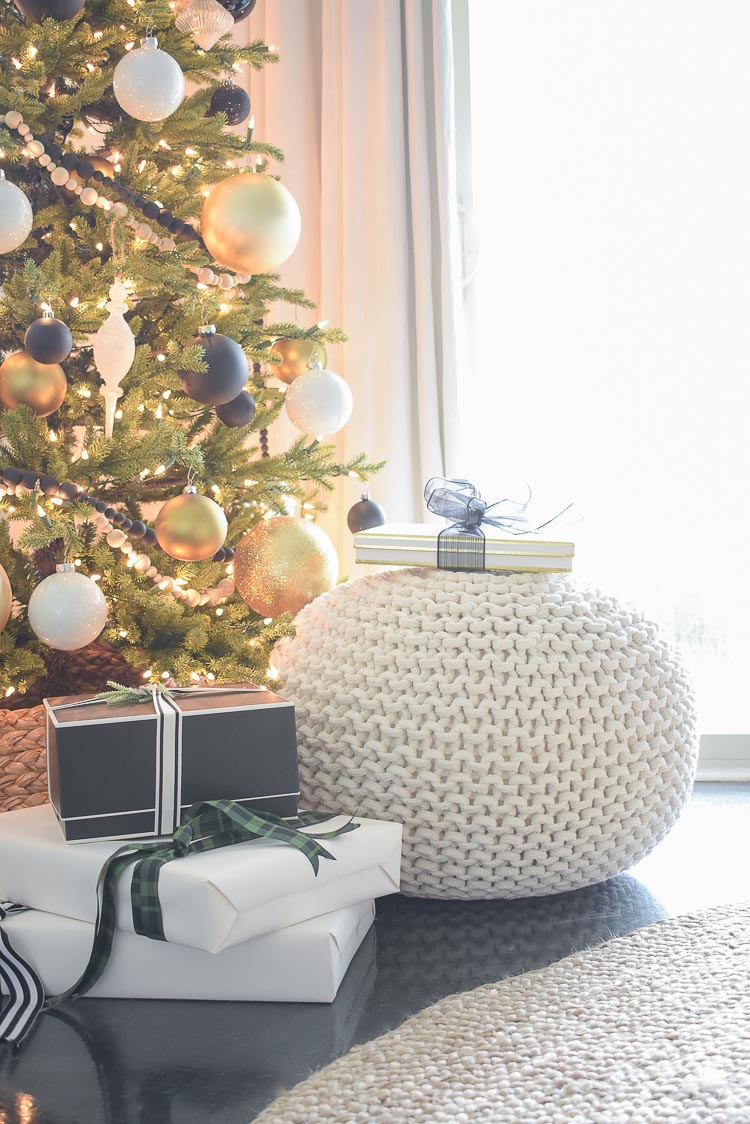 Black and white modern gift wrap / white knit pouf styled under tree for Christmas