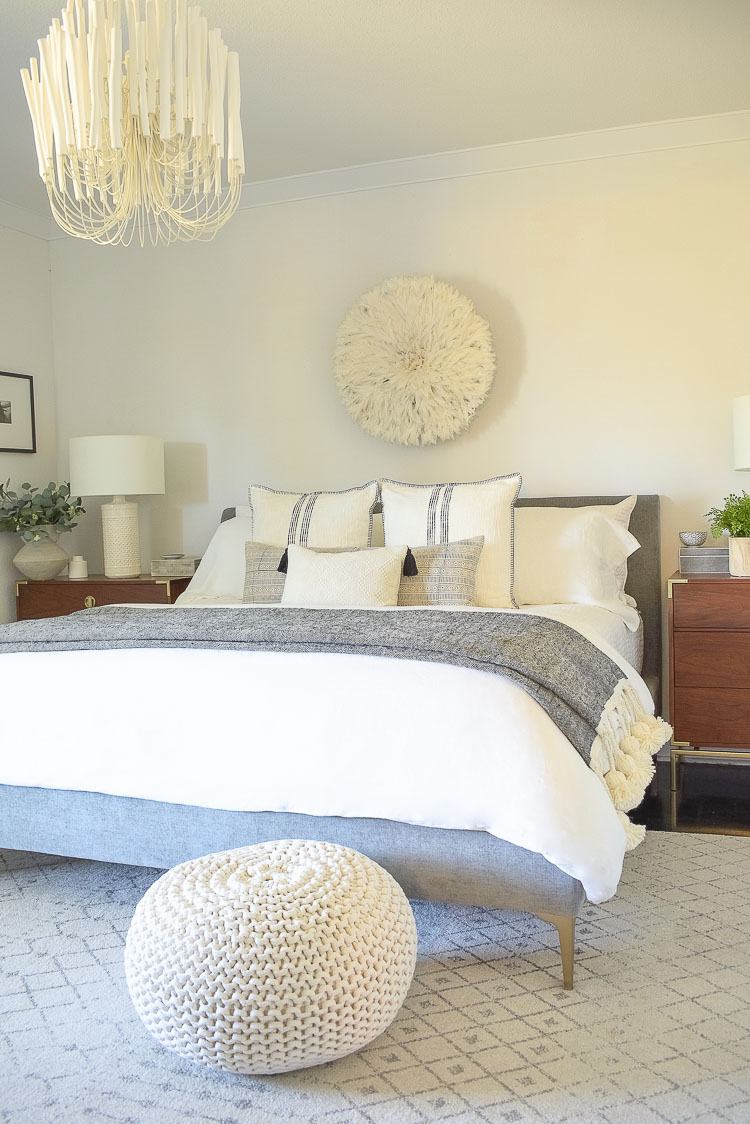 black and white spring bedroom tour - white linens, juju hat, white pouf, large tassel throw 