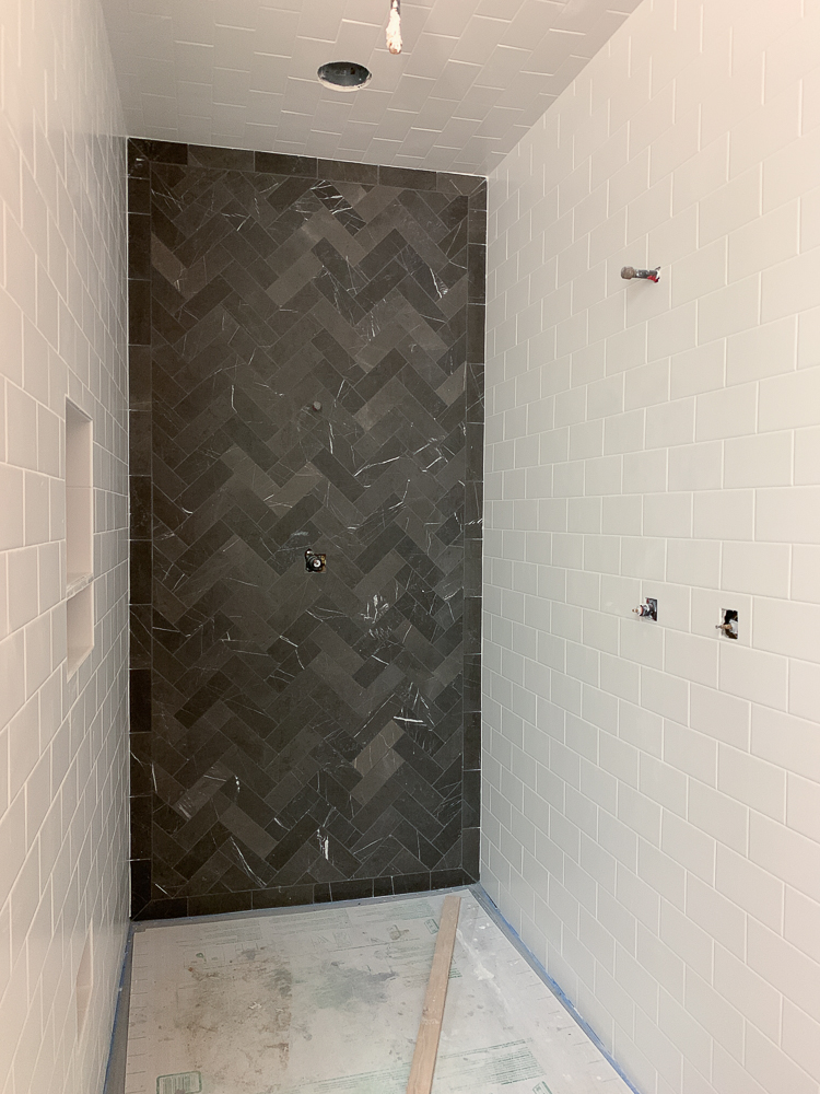 shower with white subway tile and black marble herringbone 