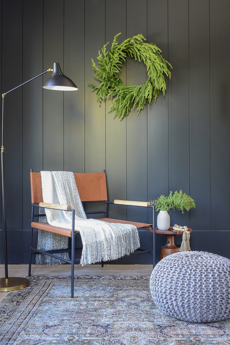 Modern leather sling chair in from of black vertical shiplap wall