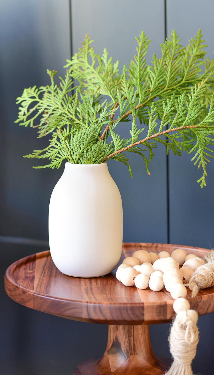 modern vase styled with wooden beads on side table 