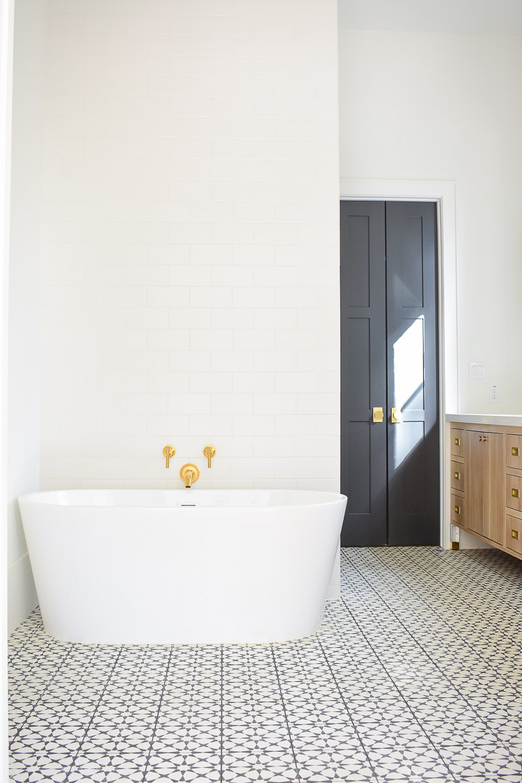 Free standing tub, black and white cement tile, white subway tile wall behind tub