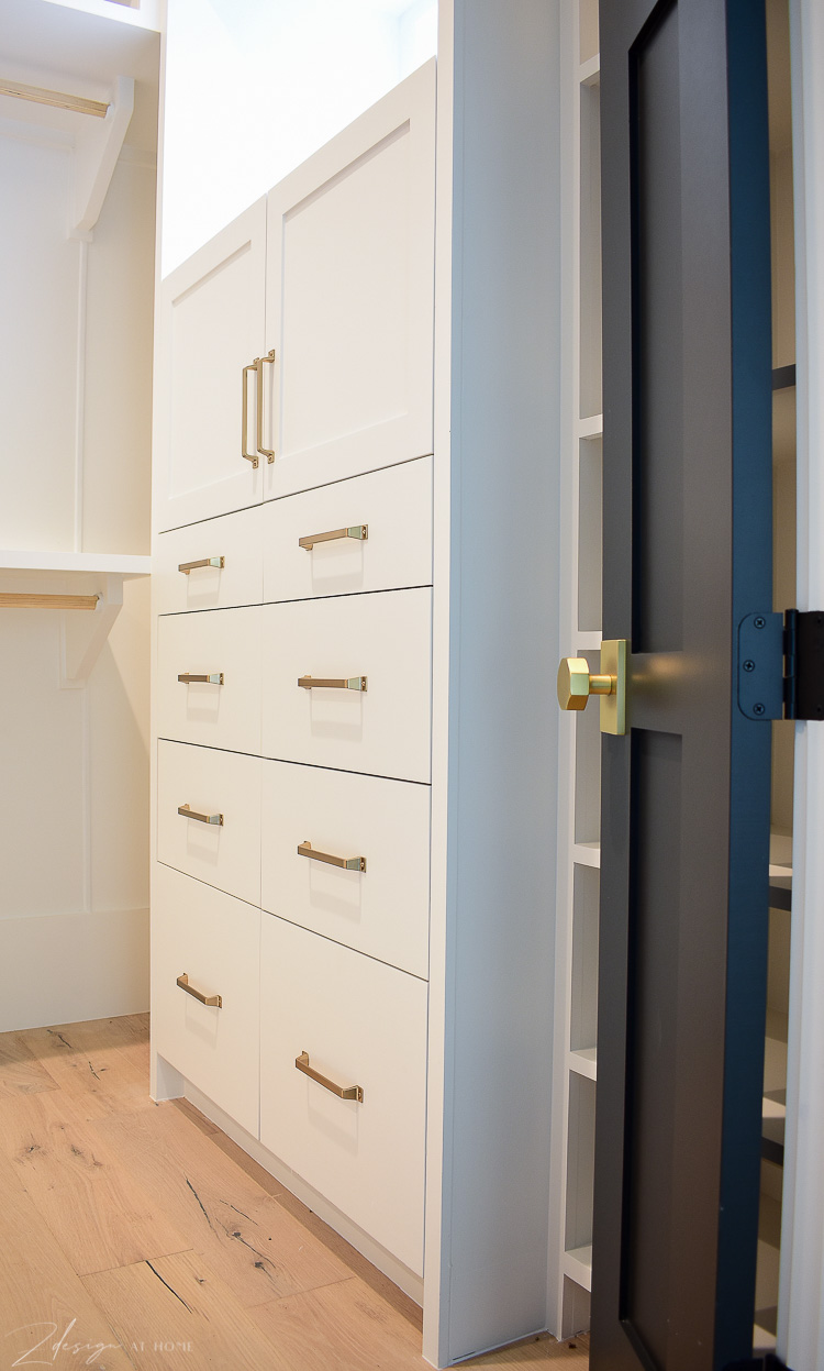 white cabinets in custom closet with brass hardware