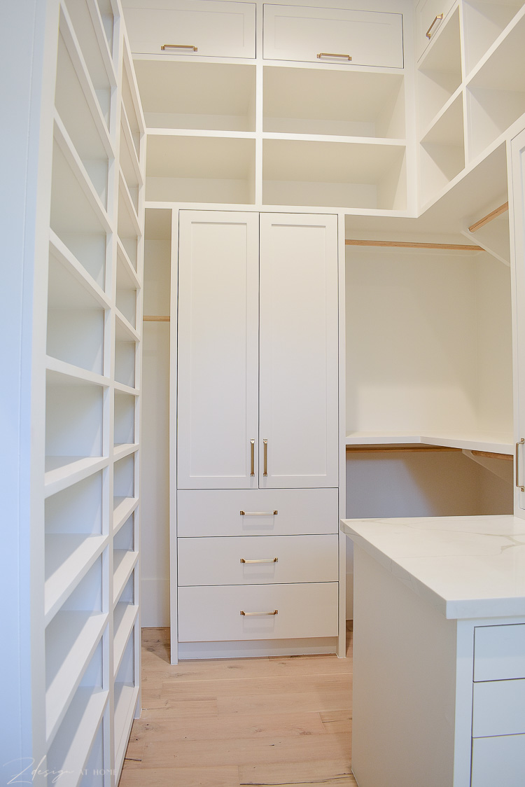 White cabinets in closet with brass hardware, closet design