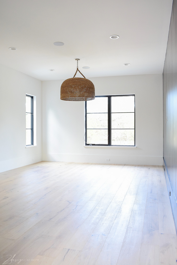 Game room with large basket pendant, white oak floors and black vertical shiplap wall