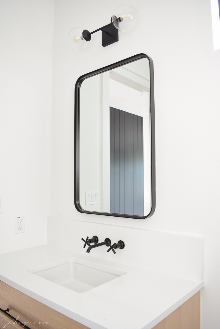 Studio Magee black metal mirror, kohler purist wall mount faucet in black, black double globe sconce 