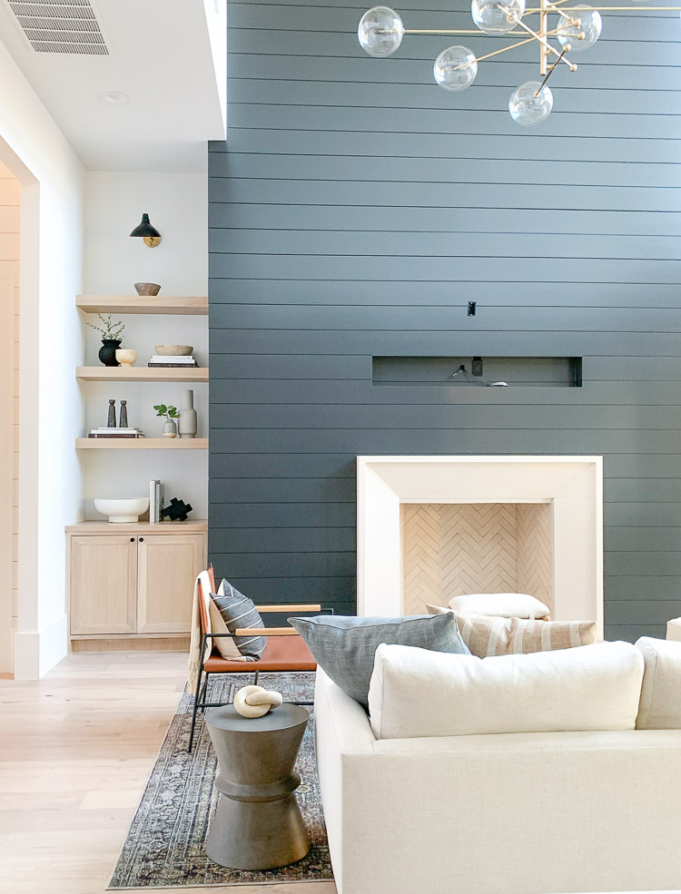 living room with black shiplap fireplace wall and white oak styled shelves 