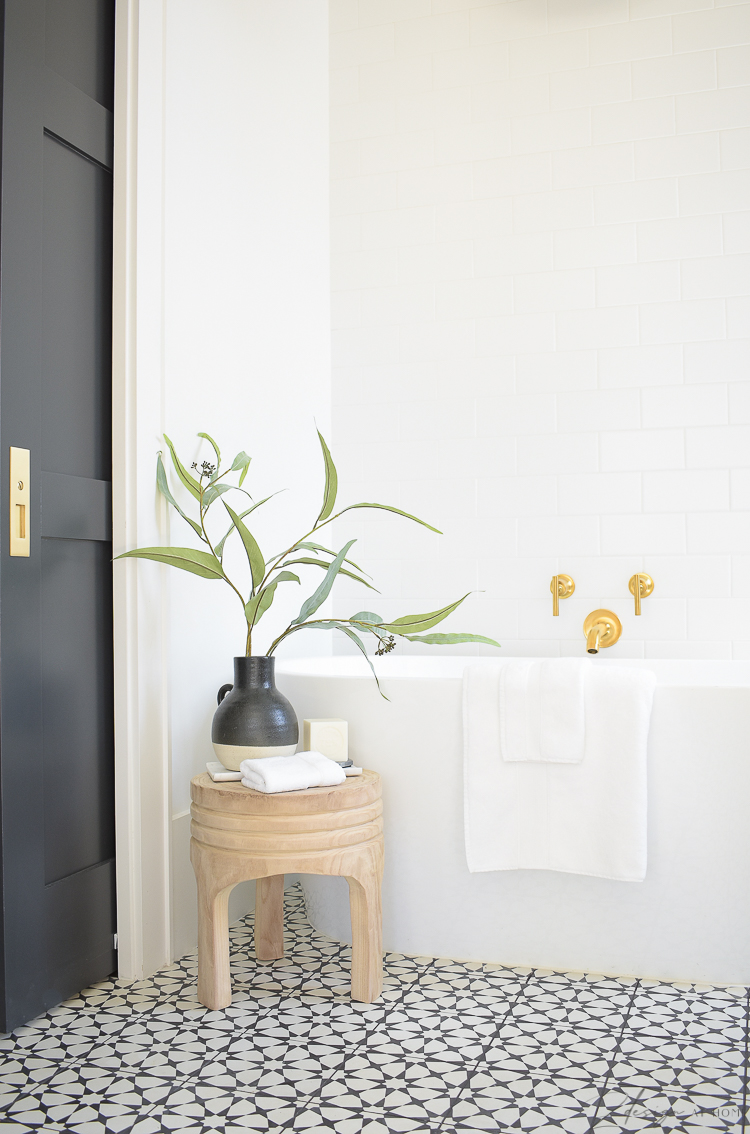 bathroom with stool style with decor in front of free standing tub, white tiled wall