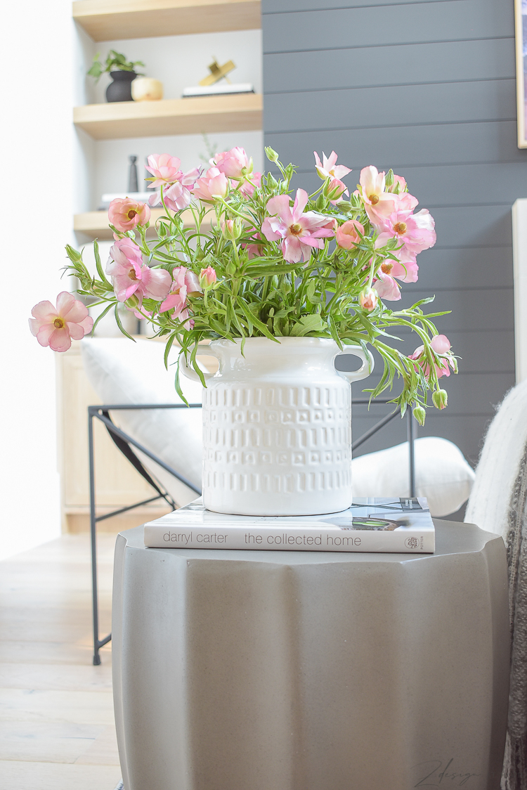 pink spring flowers in white vase on concrete side table 