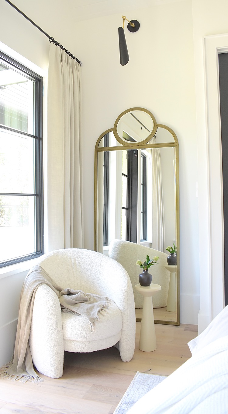 master bedroom sitting area with boucle chair and concrete side / drink table 