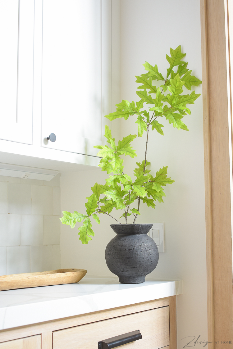 black vase with oak stem in white oak kitchen