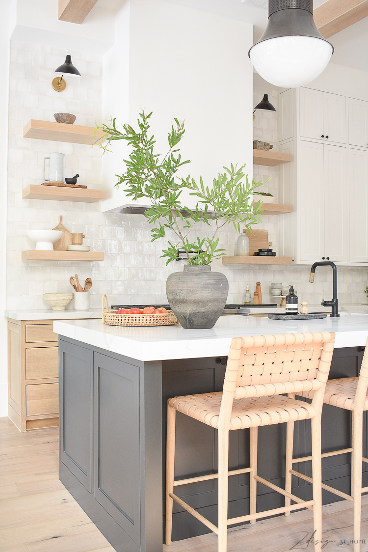 transitional modern kitchen with vintage inspired vase on counter. white oak cabinets, black island white uppers with white oak shelves 