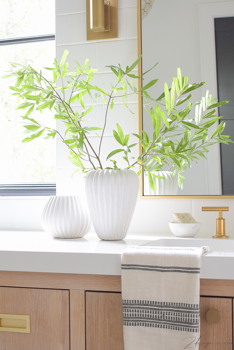 pair of white ribbed west elm vases on bathroom countertop 