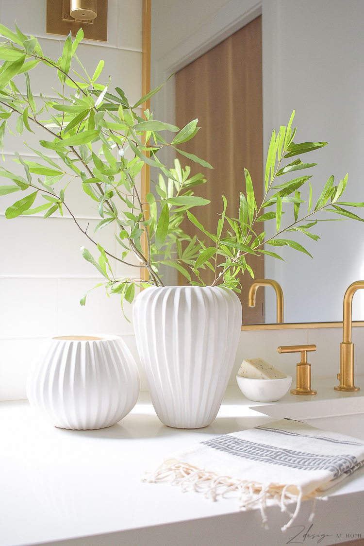 pair of white ribbed vases on bathroom countertop 