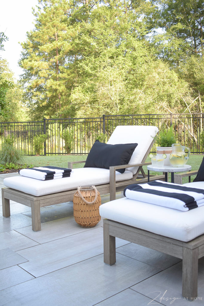 black and white striped beach pool towels, black lumbar pillow on outdoor pool lounger