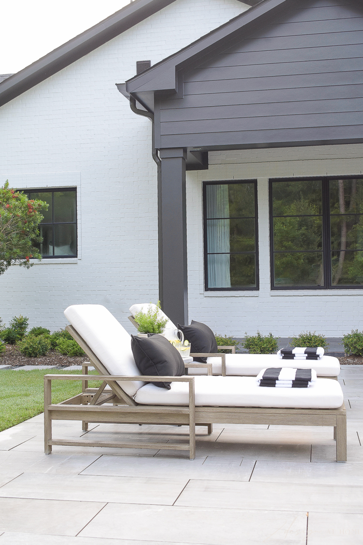 black and white outdoor decor - loungers with striped pool towels, black and white house pool area 