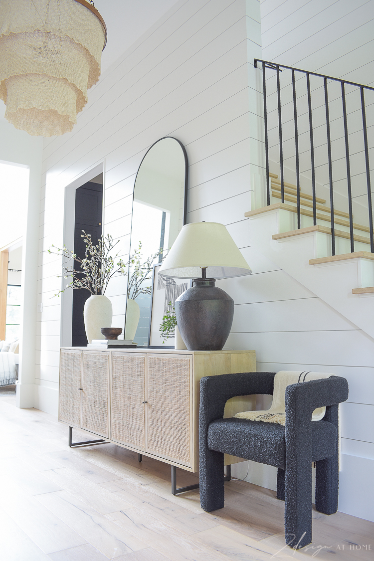 boucle chair styled next to cane console in entryway - upscale boho styling 