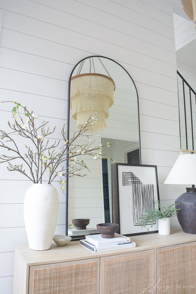 large arched floor mirror and decor on cane console table 