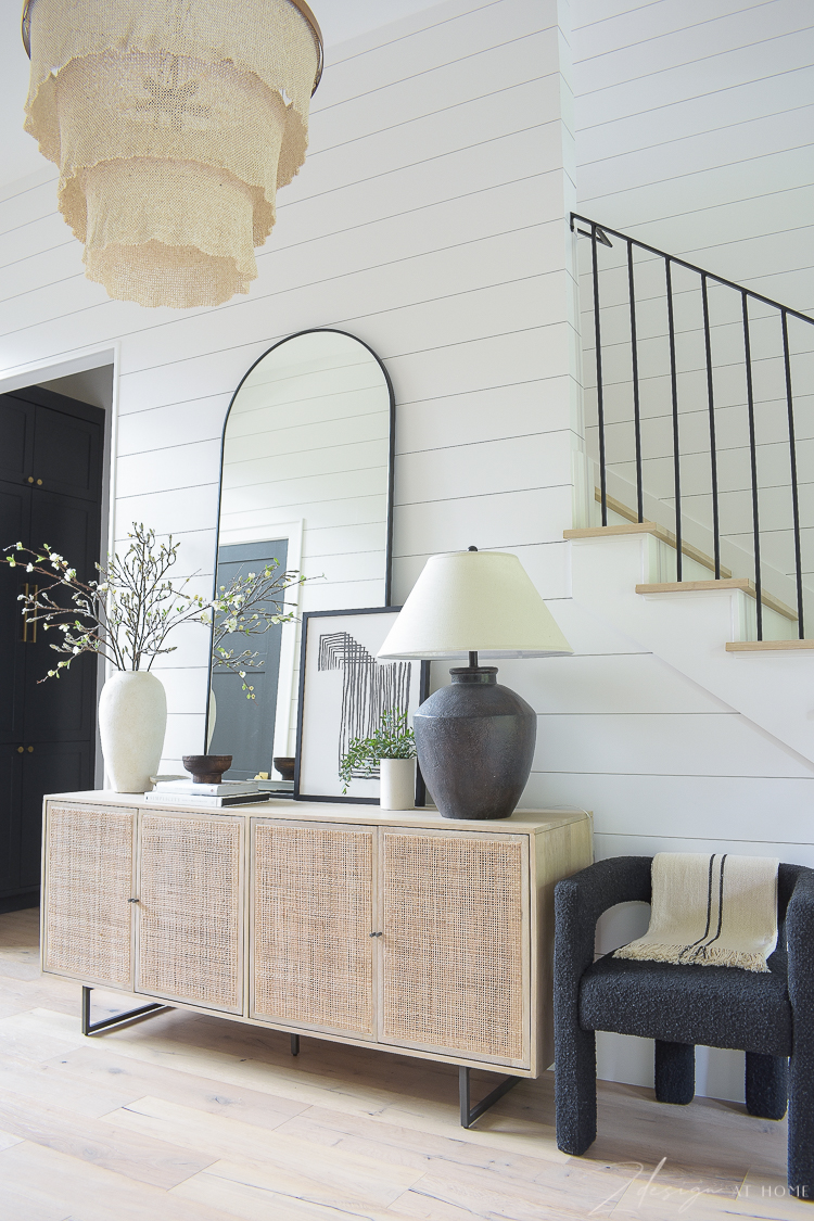 entryway hall with cane console table decorated with large mirror, art and decor