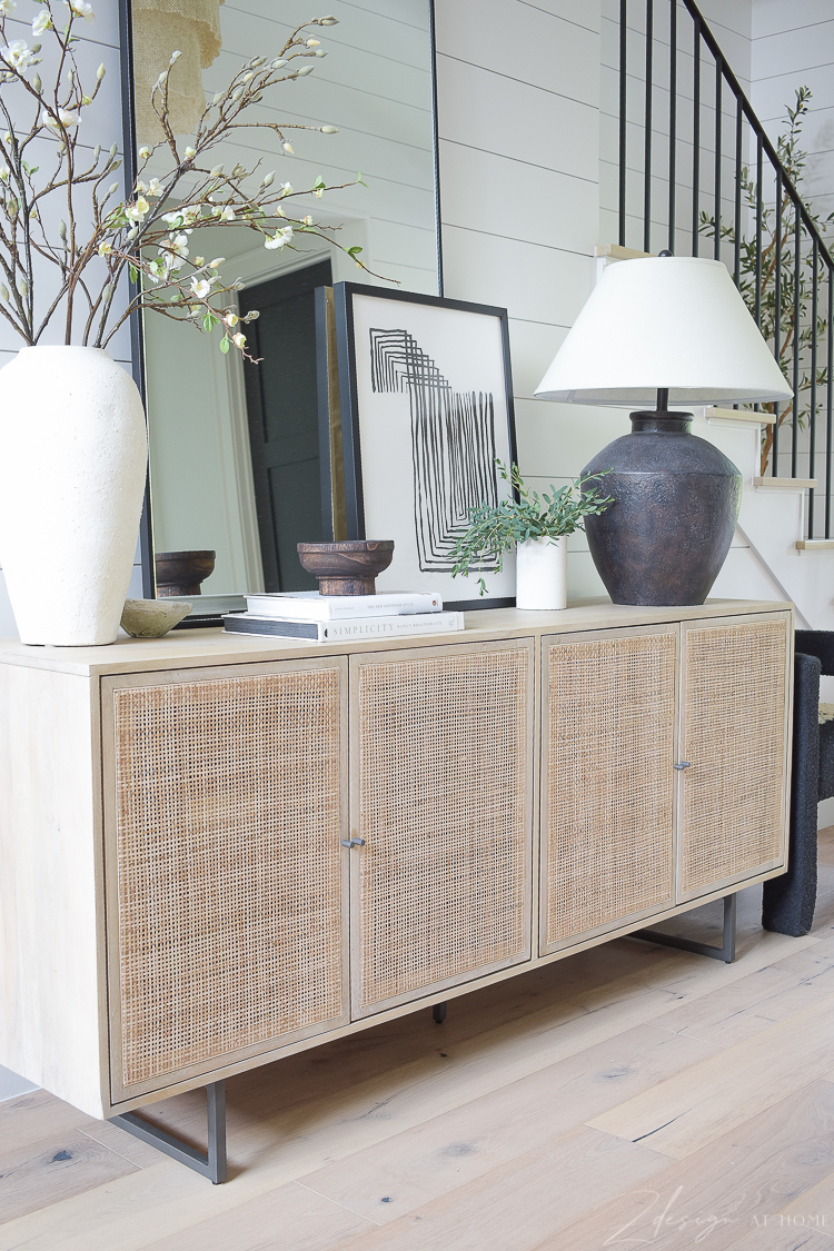 Cane console table in entry way with mirror and decor 