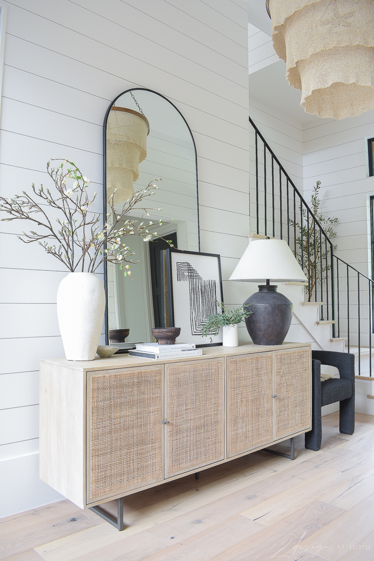 cane console with arched mirror and decor in entryway 