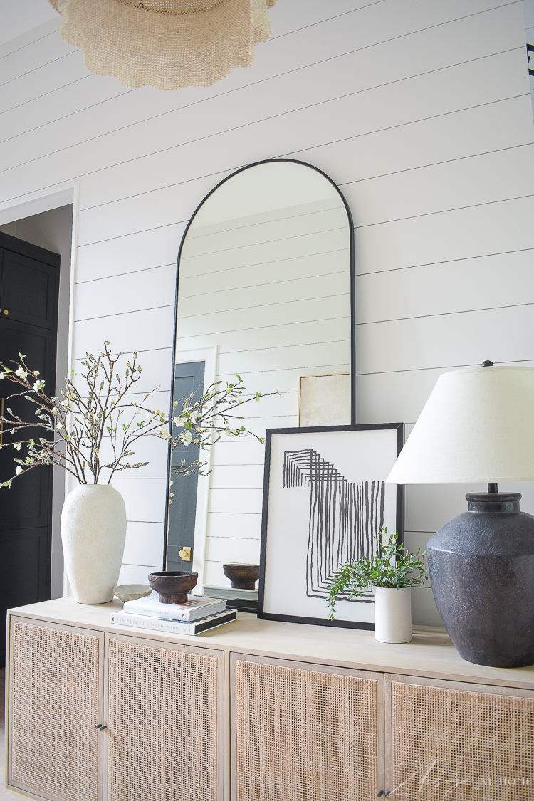 Cane console with large floor mirror and decor atop