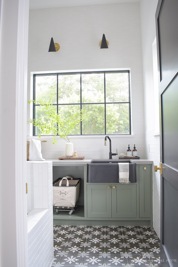 gorgeous laundry room with black white patterned tile floor and gray green cabinets 