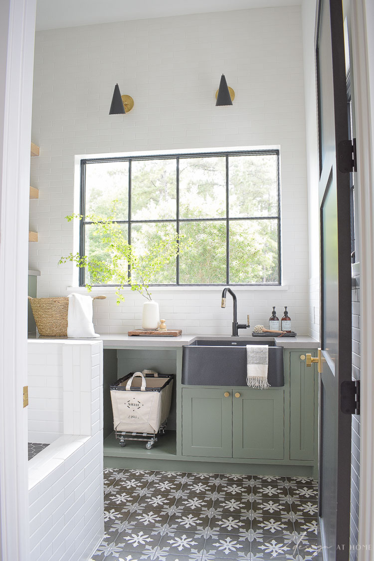 beautiful laundry room with gray green cabinets and tile to ceiling 