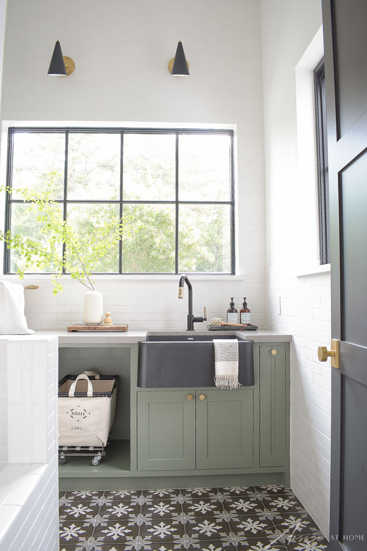 elegant laundry room, black sink, white tiled wall with black door 