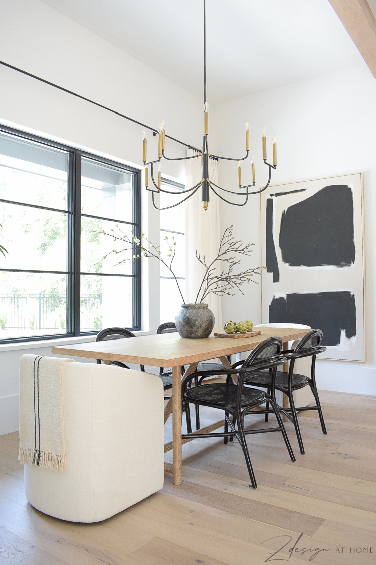 black and white modern farmhouse dining room with oversized art and rattan black chairs 