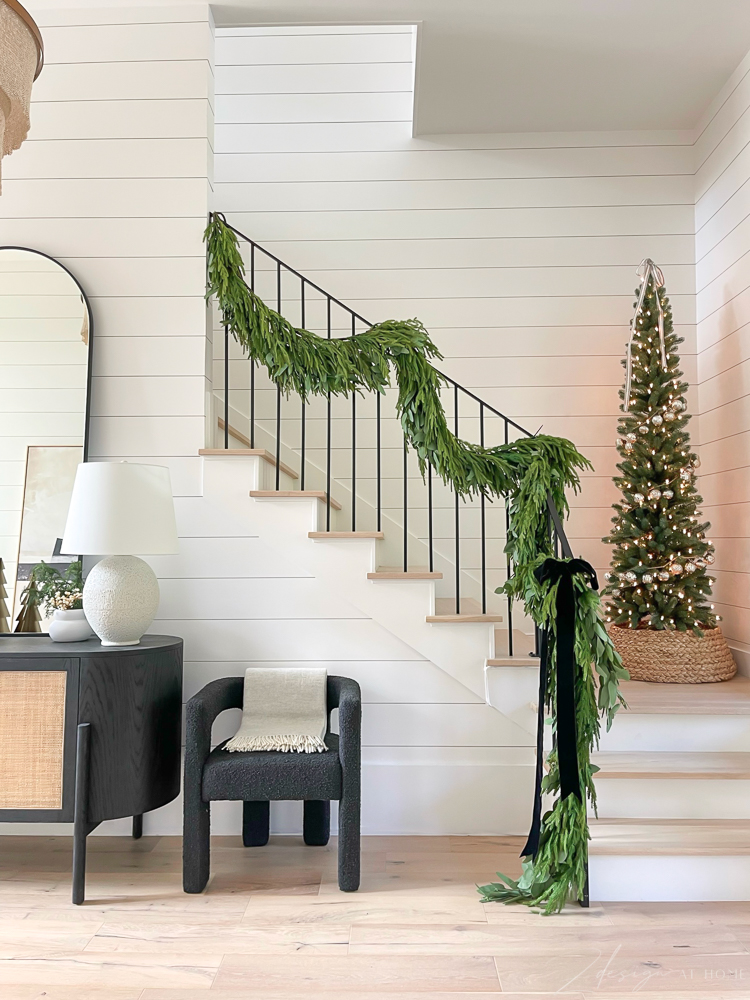 christmas holiday staircase with 3 layers of garland, eucalyptus, cedar and black velvet bow