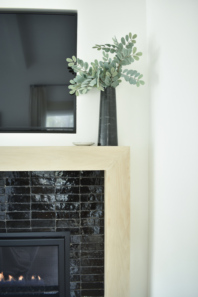 white oak mantle with black Cle Tile laid in a stacked pattern 