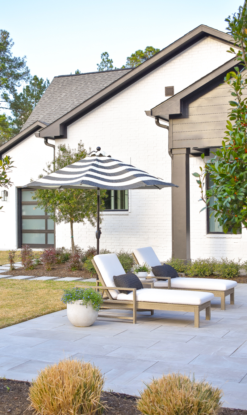 modern outdoor space pool loungers and gray pool pavers black and white house exterior 