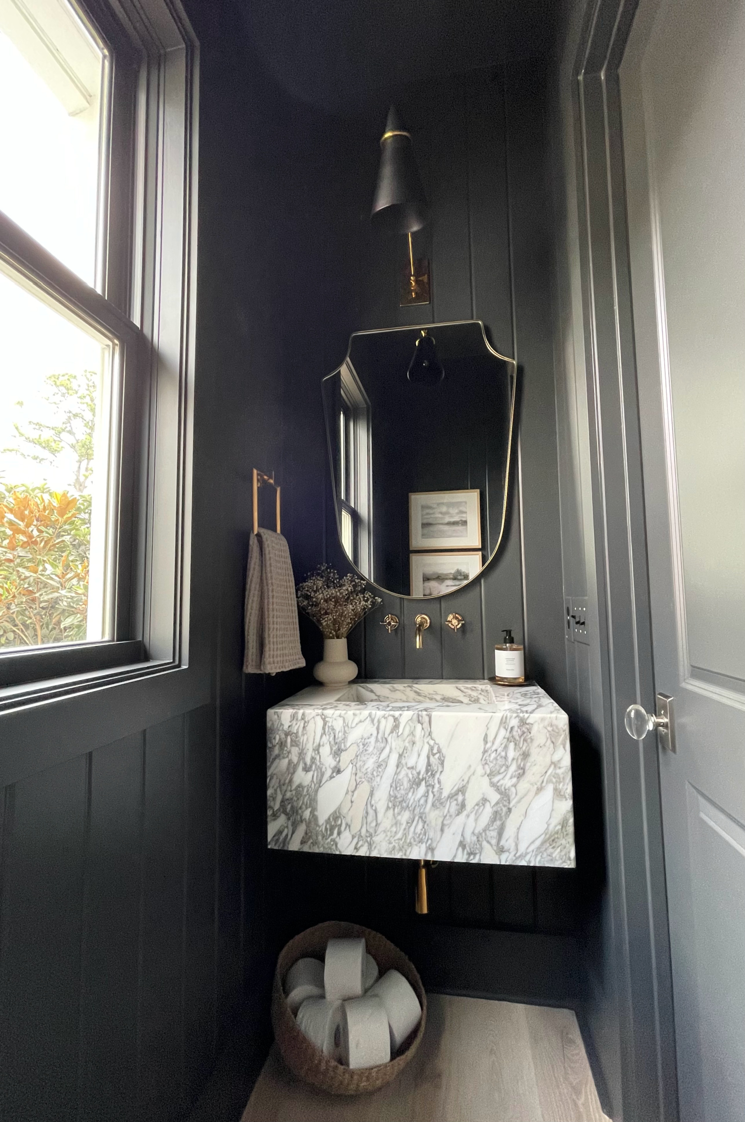 black tongue and groove powder room with arabesque marble floating sink with exposed brass pipes