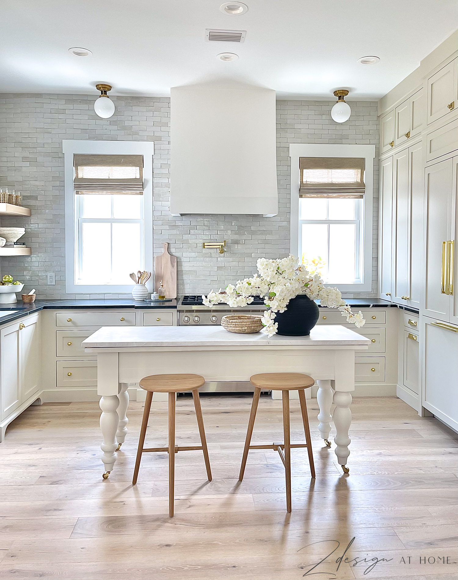 english inspired kitchen with black marble countertops and cream cabinets and french range hood 