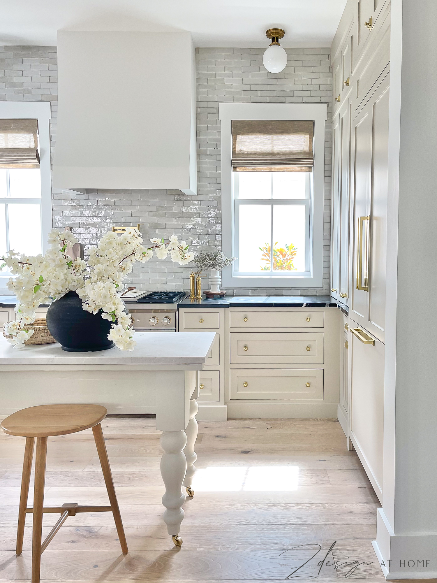 english cottage kitchen with ben moore natural cream cabinets and black marble countertops. zellige tile backsplash and french range hood