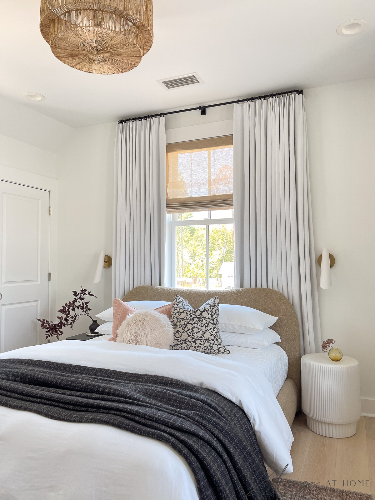 guest bedroom in cottage with transitional modern decor neutral bedding and white linen curtains 